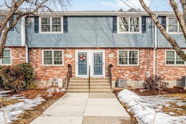 townhome / multi-family property with entry steps, cooling unit, and brick siding