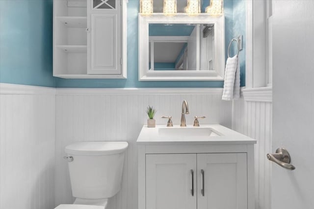 bathroom featuring toilet, vanity, and wainscoting