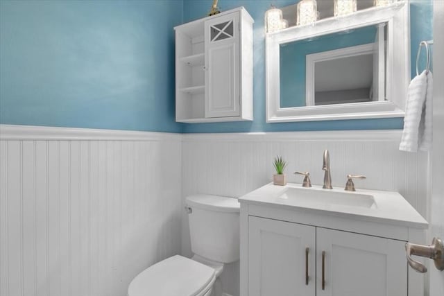 bathroom featuring a wainscoted wall, toilet, and vanity