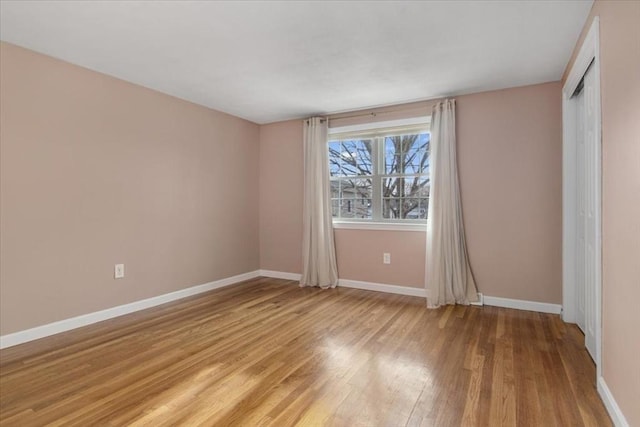 unfurnished bedroom with light wood-style floors, a closet, and baseboards