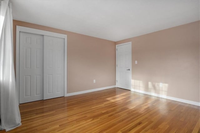 unfurnished bedroom with light wood finished floors, baseboards, and a closet