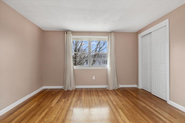 unfurnished bedroom with light wood-type flooring, a closet, and baseboards