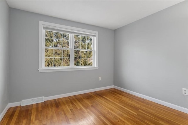 spare room featuring visible vents, baseboards, and wood finished floors