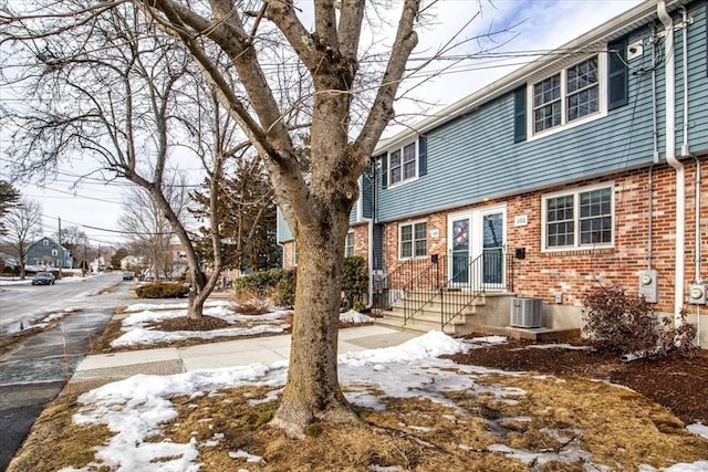 exterior space featuring brick siding and cooling unit