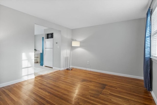 unfurnished room with baseboards, visible vents, and wood finished floors