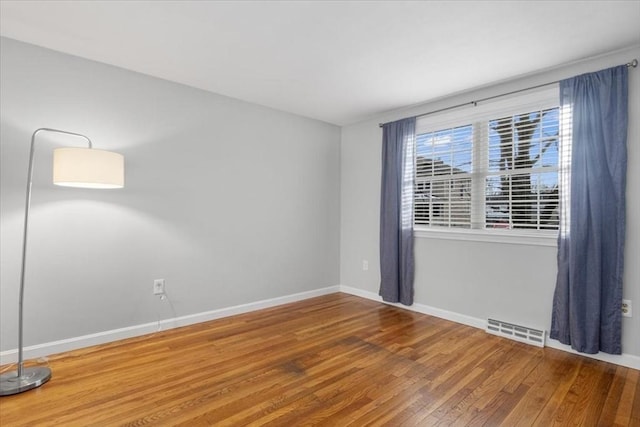 unfurnished room with visible vents, baseboards, and wood finished floors