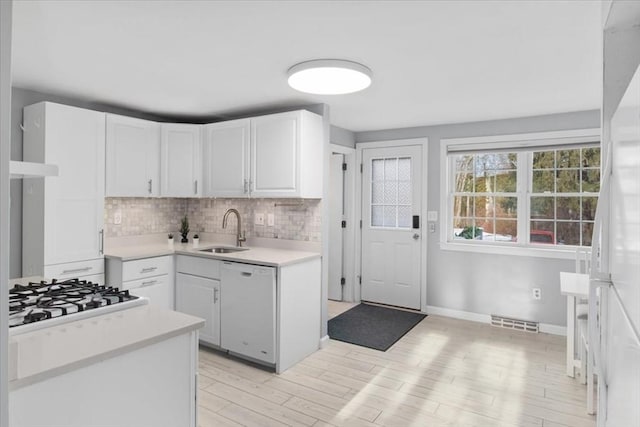 kitchen featuring white appliances, visible vents, light countertops, white cabinetry, and a sink