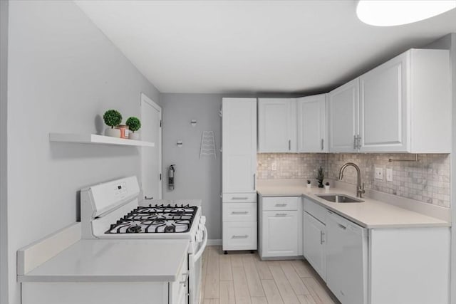 kitchen featuring white appliances, a sink, white cabinets, light countertops, and decorative backsplash