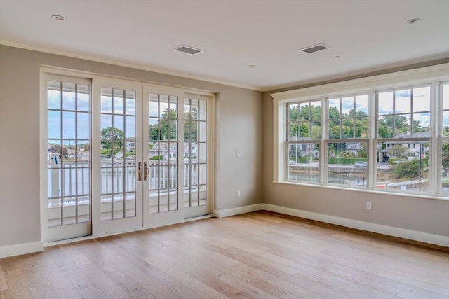 doorway with ornamental molding, light hardwood / wood-style floors, french doors, and a healthy amount of sunlight