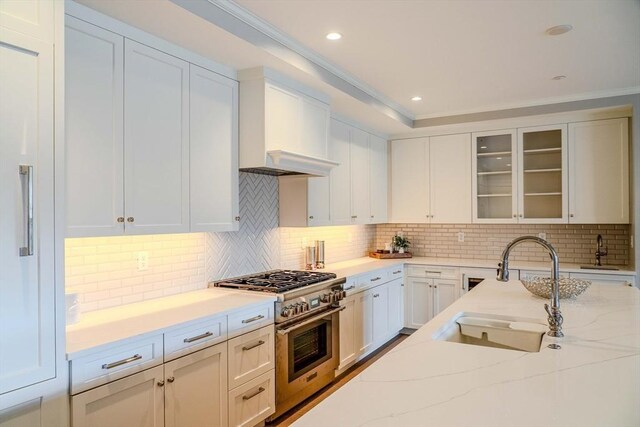 kitchen with white cabinets, ornamental molding, high end stainless steel range, and light stone counters