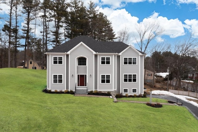 view of front of house with entry steps, roof with shingles, and a front lawn