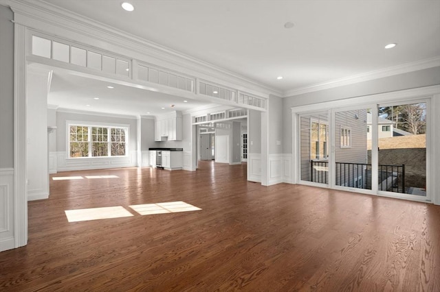 unfurnished living room featuring ornamental molding, dark wood finished floors, and a decorative wall