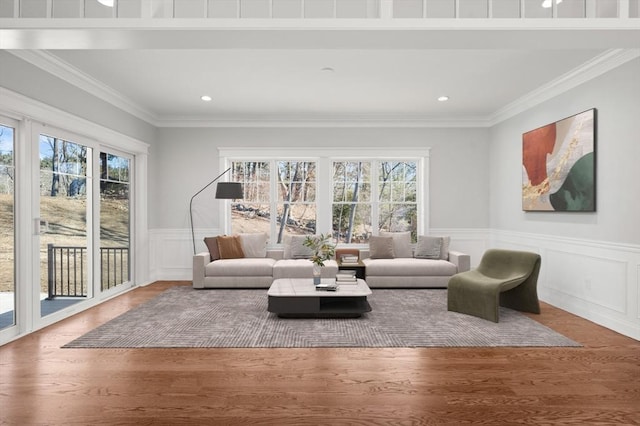 living area with a wainscoted wall, wood finished floors, and crown molding