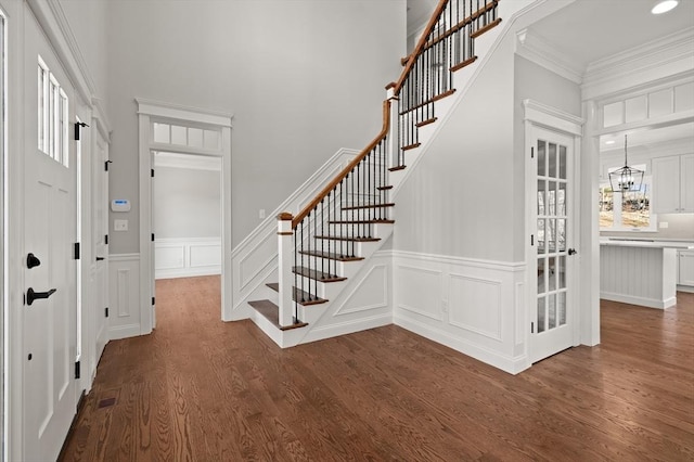 foyer entrance featuring stairway, dark wood-type flooring, an inviting chandelier, crown molding, and recessed lighting