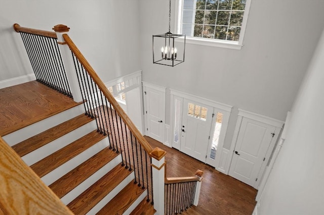 foyer entrance with stairway, a chandelier, a decorative wall, and wood finished floors