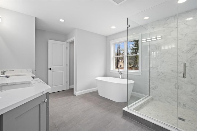 bathroom with a stall shower, a freestanding tub, baseboards, and recessed lighting