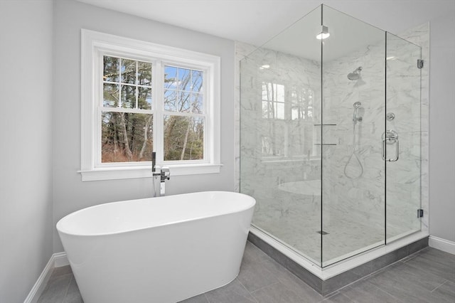 full bathroom featuring a stall shower, a freestanding tub, and baseboards