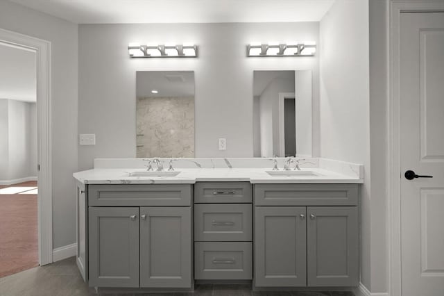 full bathroom with double vanity, a sink, and baseboards