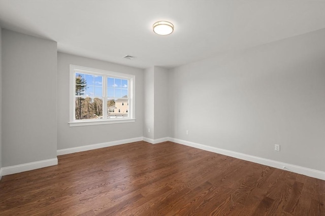 empty room with dark wood-style flooring and baseboards