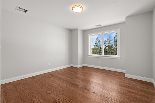 empty room featuring baseboards, visible vents, and wood finished floors