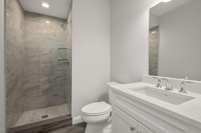 full bath featuring toilet, a tile shower, and vanity