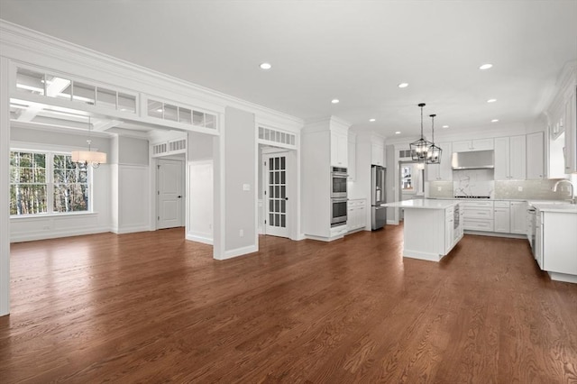 kitchen featuring a chandelier, under cabinet range hood, dark wood-type flooring, open floor plan, and appliances with stainless steel finishes