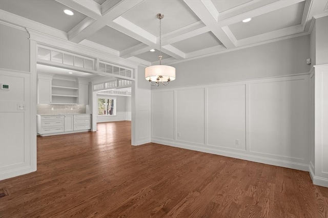 unfurnished dining area with coffered ceiling, dark wood-style flooring, a decorative wall, and beamed ceiling