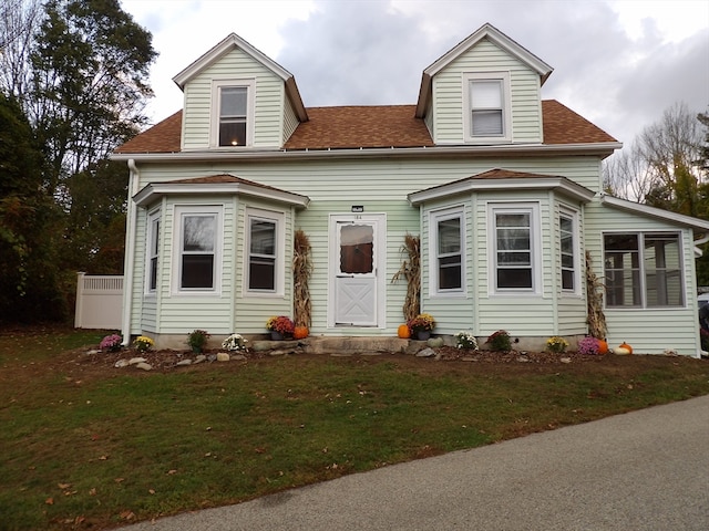 new england style home with a front yard and a sunroom