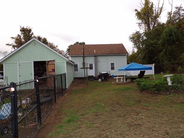 back of house featuring a yard and an outbuilding