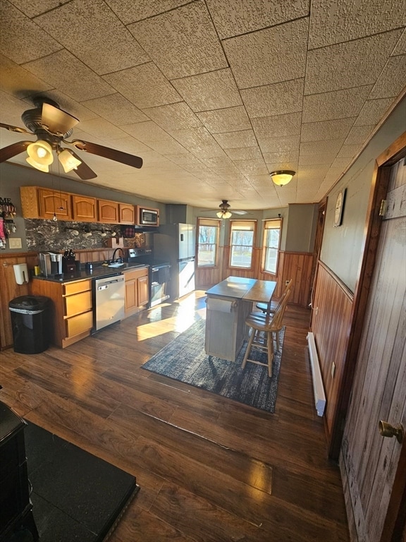 dining room featuring dark hardwood / wood-style floors, baseboard heating, wooden walls, and sink