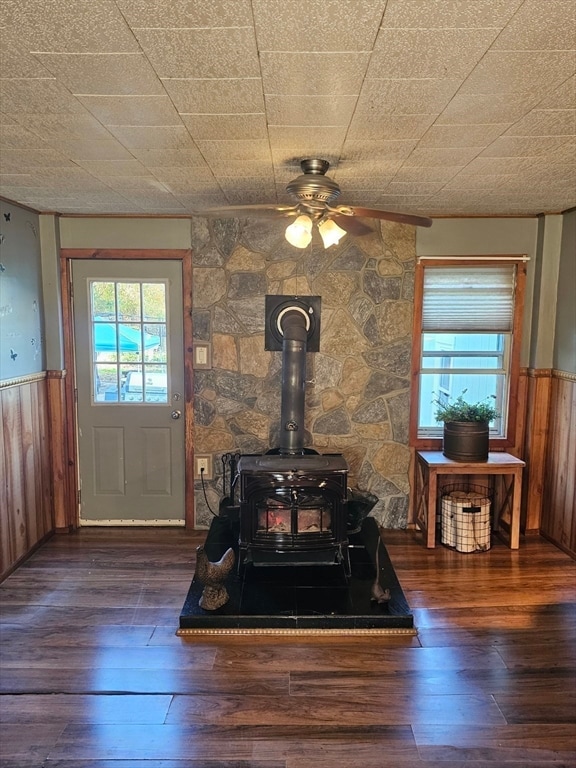 interior details featuring a wood stove, wooden walls, and wood-type flooring