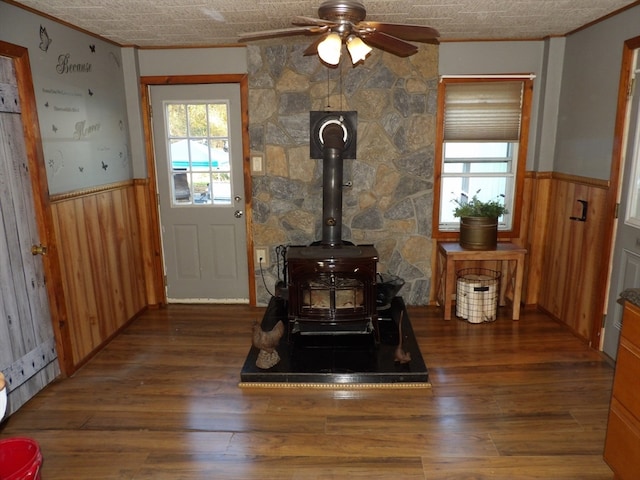 interior space featuring a wood stove, ceiling fan, hardwood / wood-style floors, and crown molding