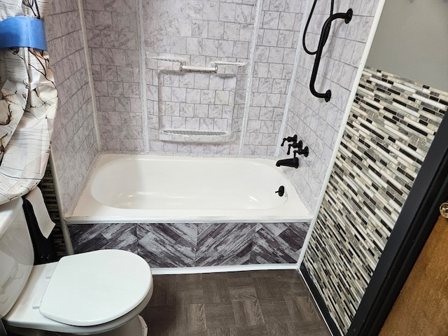 bathroom featuring tiled shower / bath combo, toilet, and parquet flooring