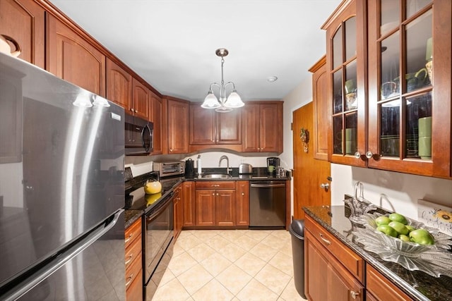 kitchen featuring appliances with stainless steel finishes, pendant lighting, a notable chandelier, dark stone countertops, and light tile patterned flooring