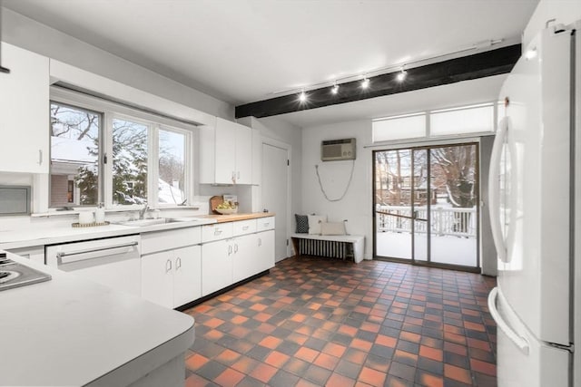 kitchen with sink, white cabinetry, beamed ceiling, and white fridge