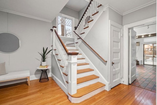 staircase with hardwood / wood-style floors and ornamental molding