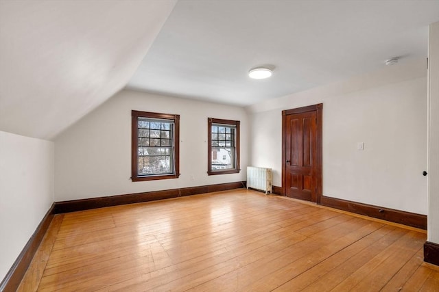 additional living space featuring light hardwood / wood-style floors, radiator, and lofted ceiling