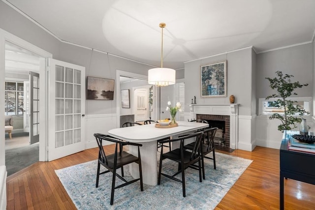 dining room featuring hardwood / wood-style flooring, crown molding, and a fireplace