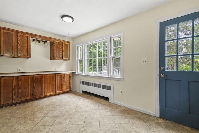 23 Ivan St, Lexington, MA 02420 - kitchen with radiator, light tile patterned flooring, light countertops, and brown cabinetry