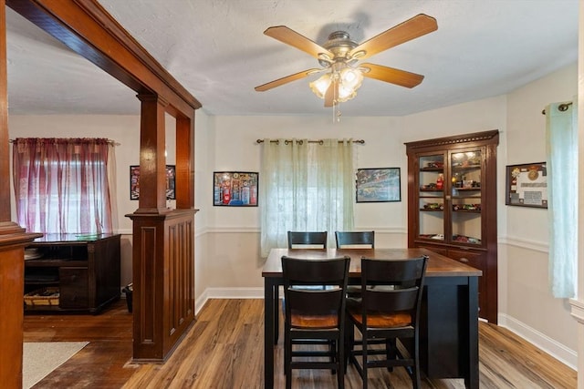 dining space with wood finished floors, a ceiling fan, and baseboards