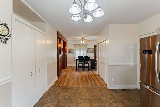 hallway with a chandelier, stone finish flooring, and baseboards