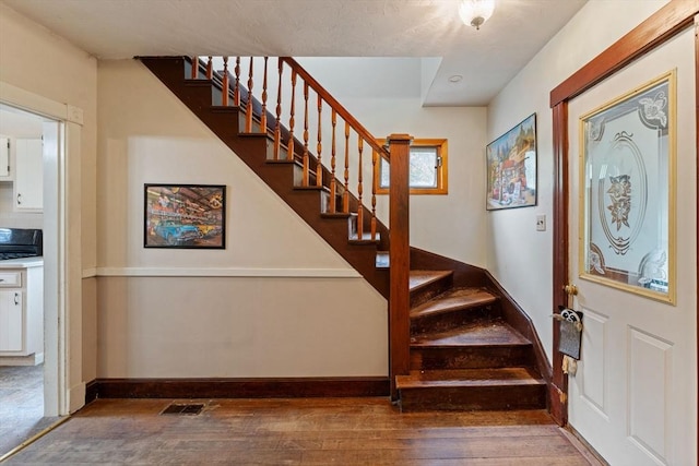 foyer with hardwood / wood-style floors, stairs, and baseboards