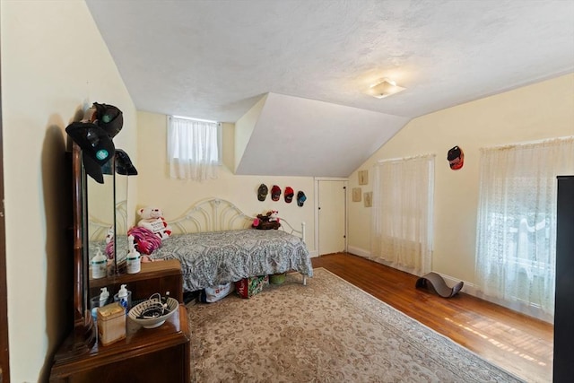 bedroom with wood finished floors, lofted ceiling, and baseboards