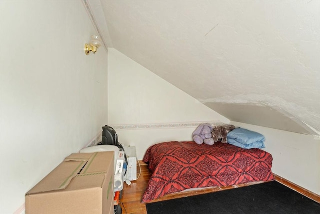 bedroom with vaulted ceiling and wood finished floors