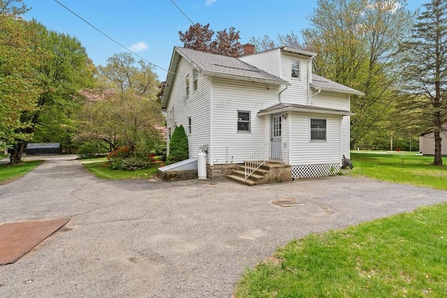 rear view of house with a chimney and a shingled roof