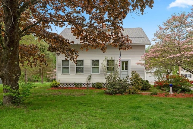 view of side of property featuring a lawn, a chimney, and roof with shingles