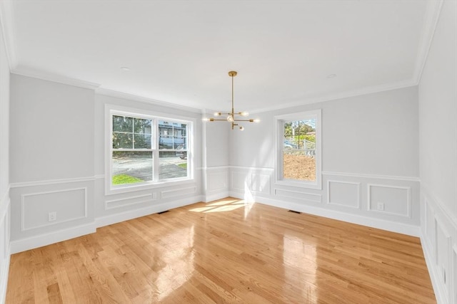 empty room featuring crown molding, light hardwood / wood-style floors, and an inviting chandelier