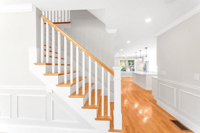 stairway featuring wood-type flooring and ornamental molding