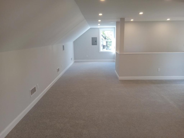 additional living space with electric panel, light colored carpet, and lofted ceiling