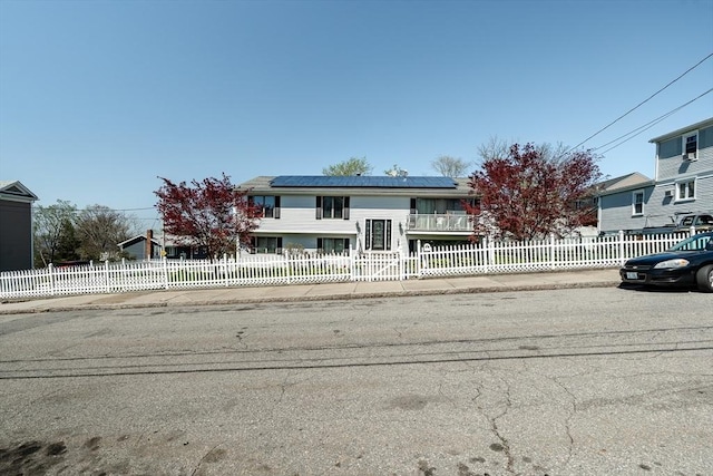 split foyer home with a fenced front yard and solar panels